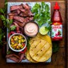 Sriracha Marinated Steak Tacos with Grilled Pineapple Salsa and Sriracha-Spiked Sour Cream